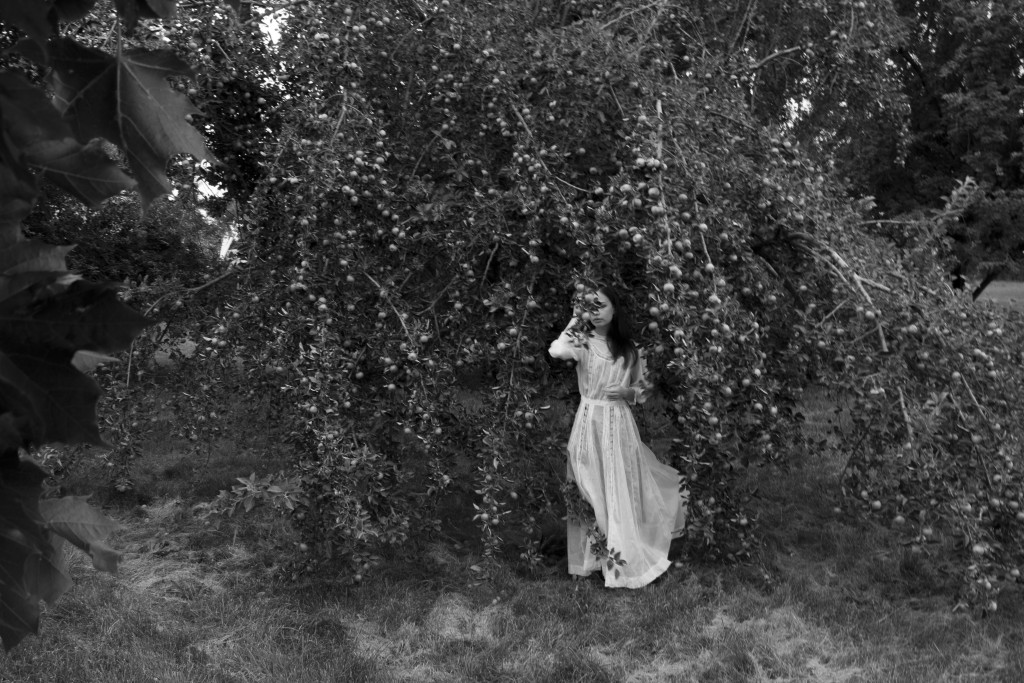 Photograph of a woman standing under a tree